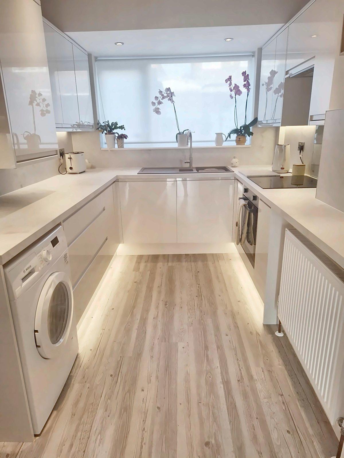 Bright white gloss fitted kitchen with orchids on the windowsill
