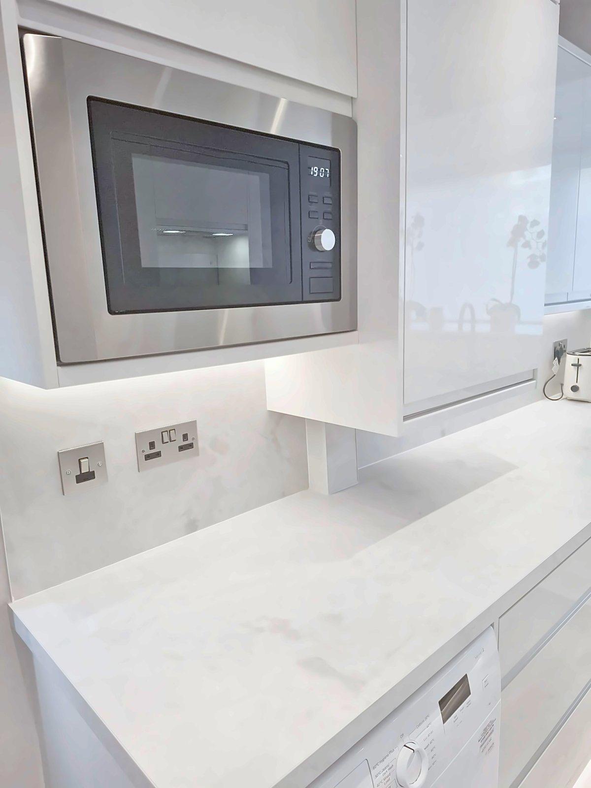 Integrated microwave and marble worktop detail in a white gloss kitchen